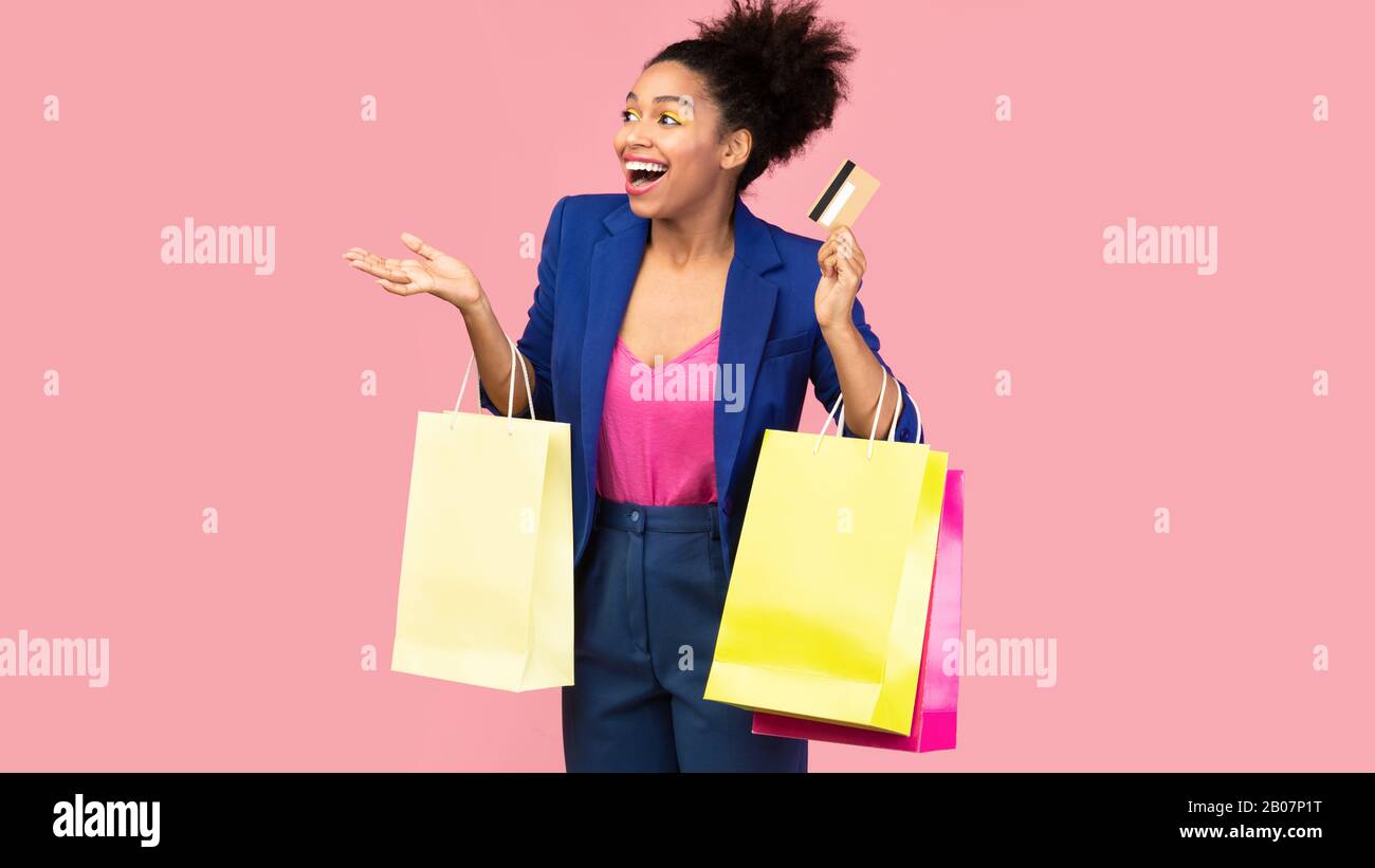 Portrait of cheerful afro girl holding shopping bags looking away Stock ...