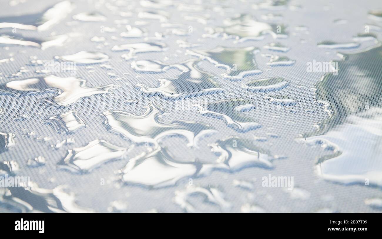 Water drops are on a white plastic fabric surface. Close-up photo with selective soft focus Stock Photo