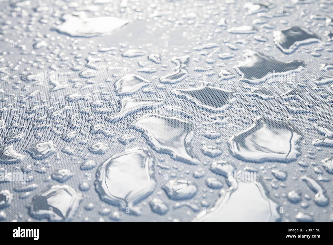 Water drops are on a white plastic fabric. Close-up photo with selective focus Stock Photo