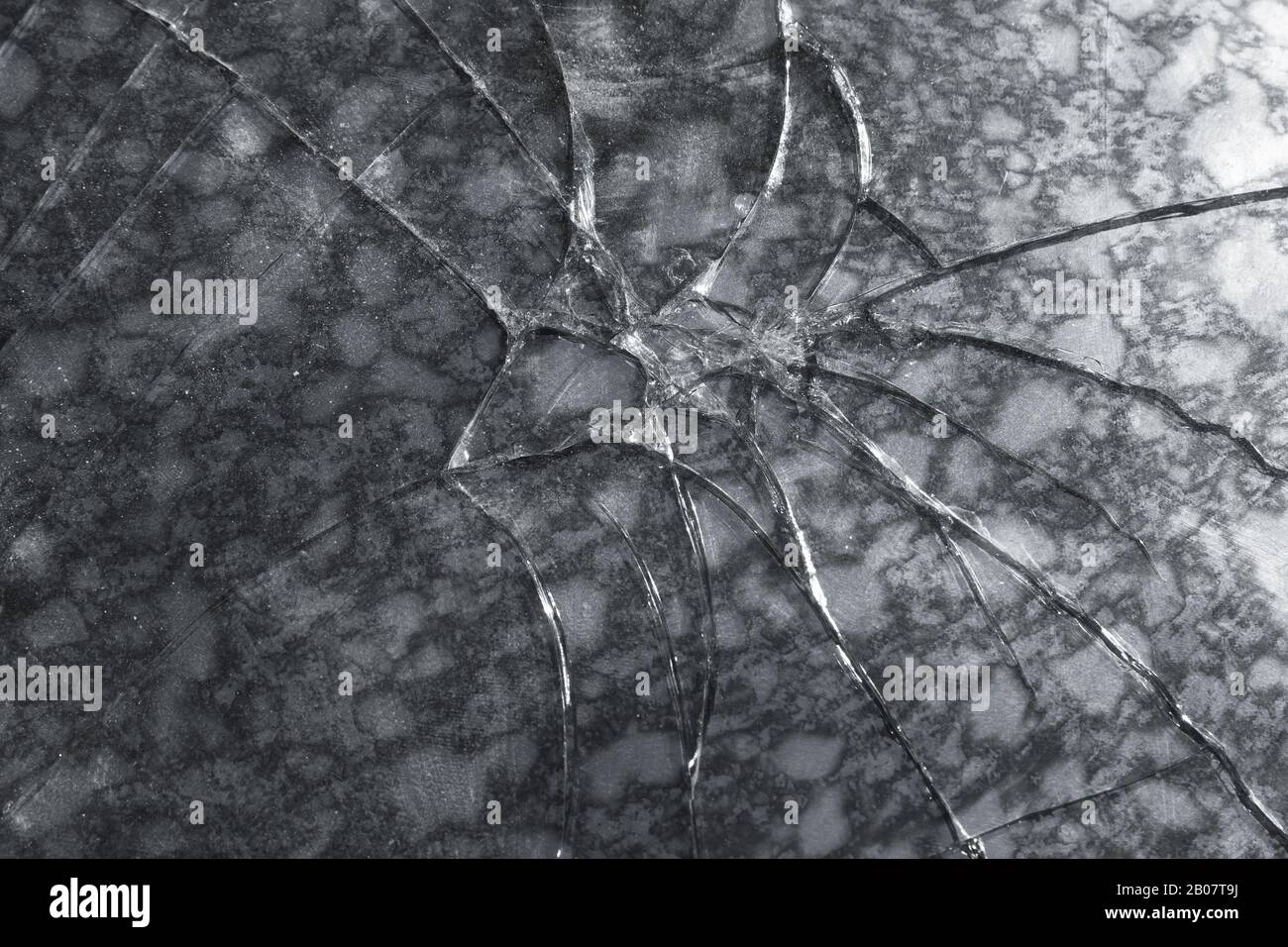 Abstract texture of a broken glass sheet over dark stone background Stock Photo