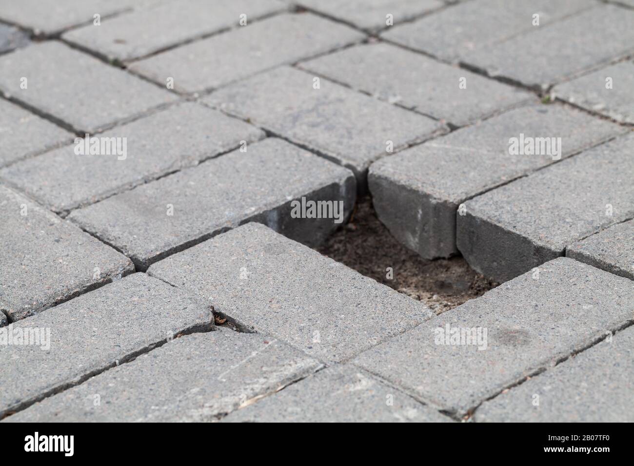 Gray cobblestone road pavement with hole of missed block, close-up photo with selective soft focus Stock Photo