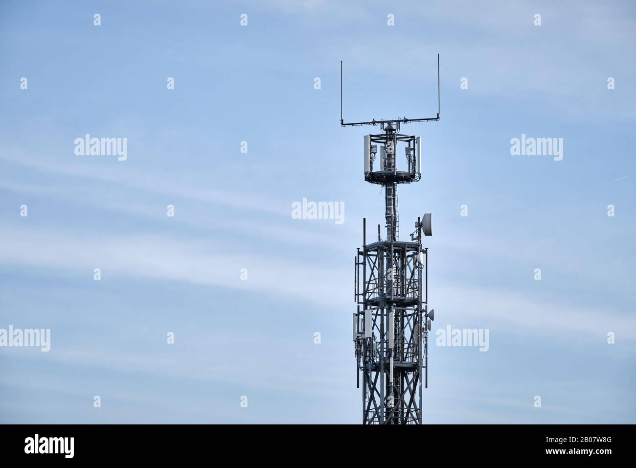 Close-up of lattice mast with base station for mobile communications against blue sky with clouds. Seen in Germany in February Stock Photo
