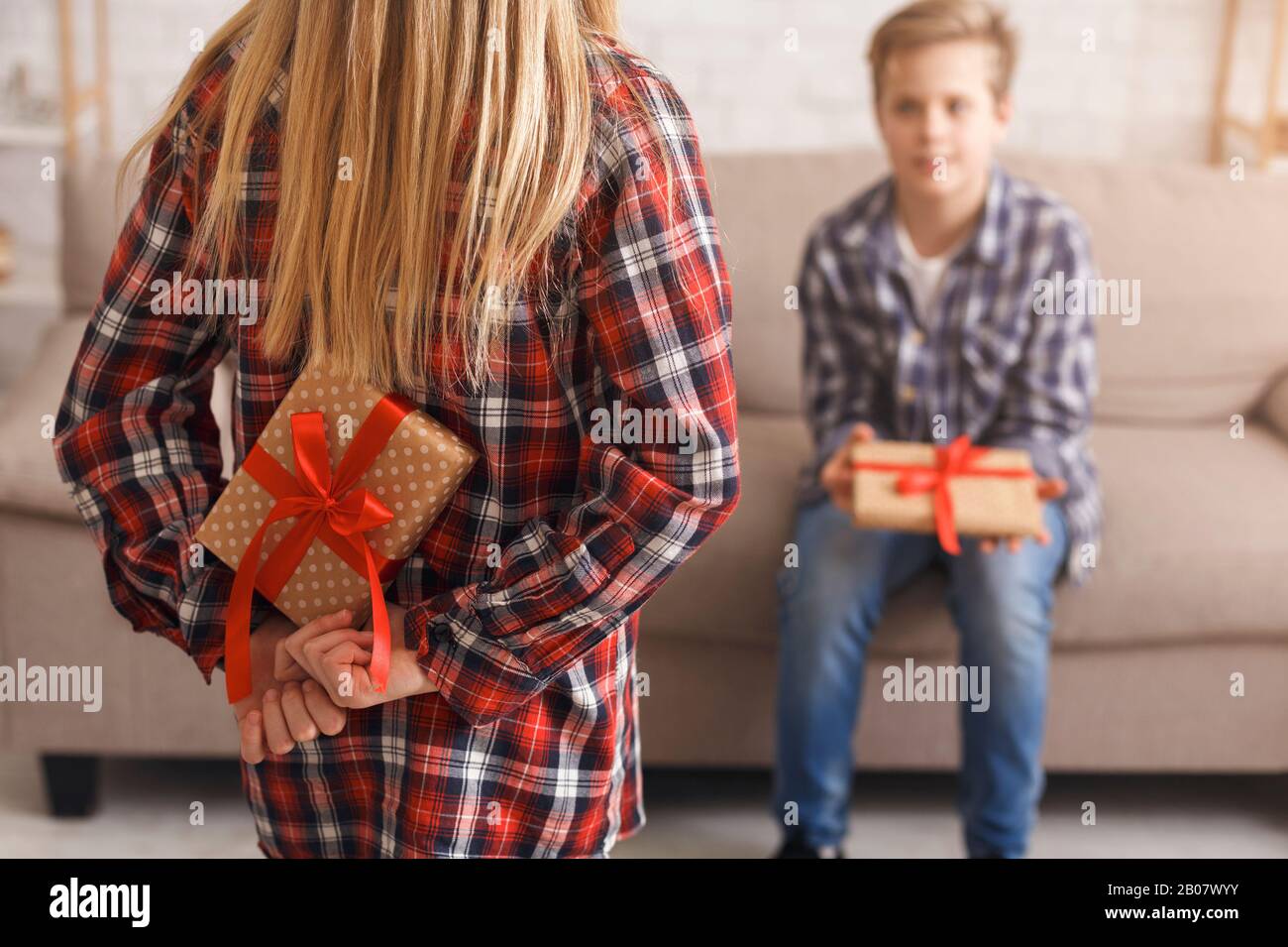 Unrecognizable Girl Holding Gift For Brother Standing At Home, Cropped Stock Photo
