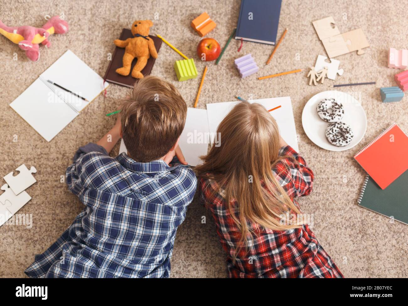 Unrecognizable Brother And Sister Drawing Together Lying On Floor Stock Photo