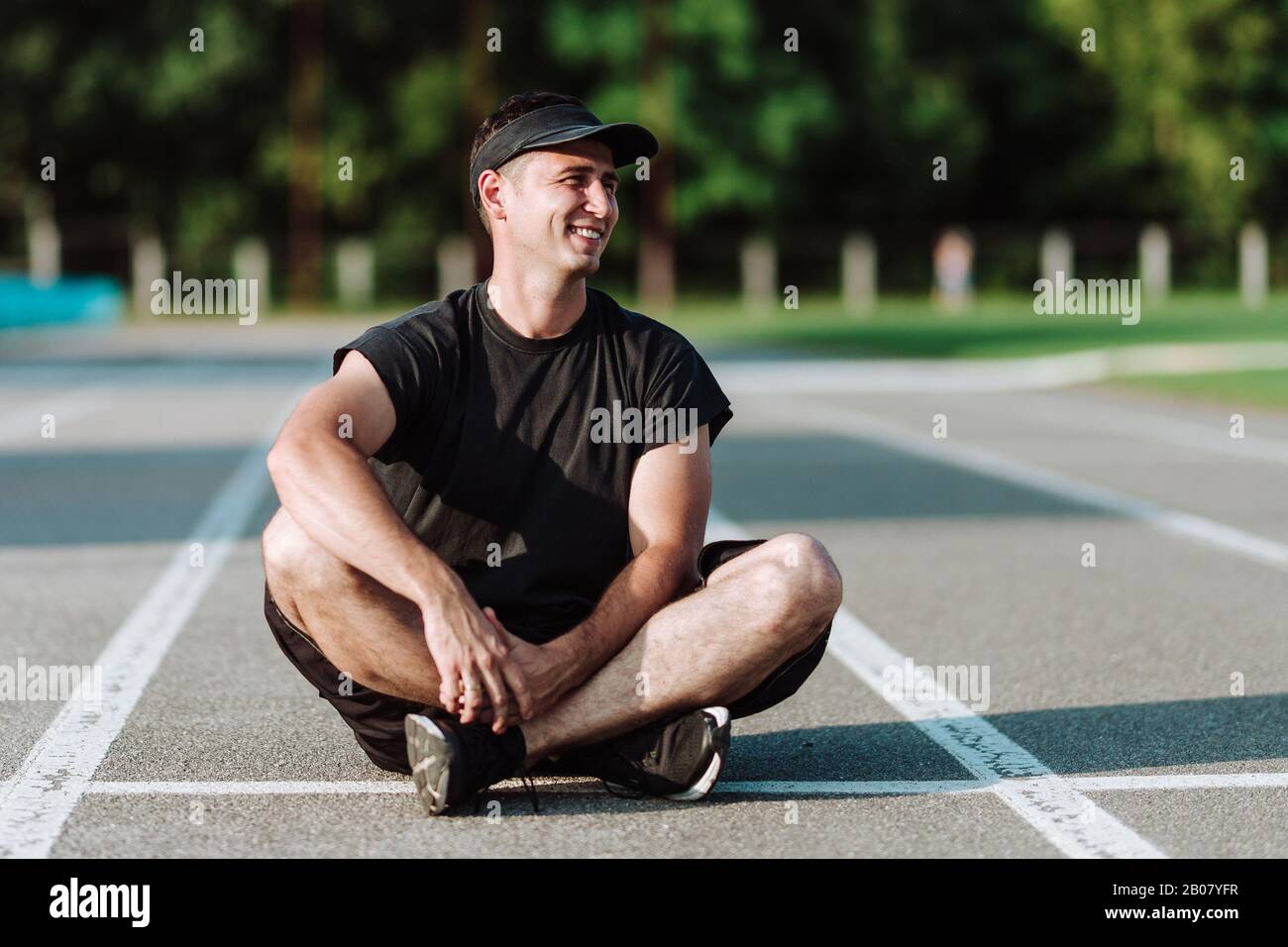 Young handsome guy smiles while sitting on the floor Stock Photo