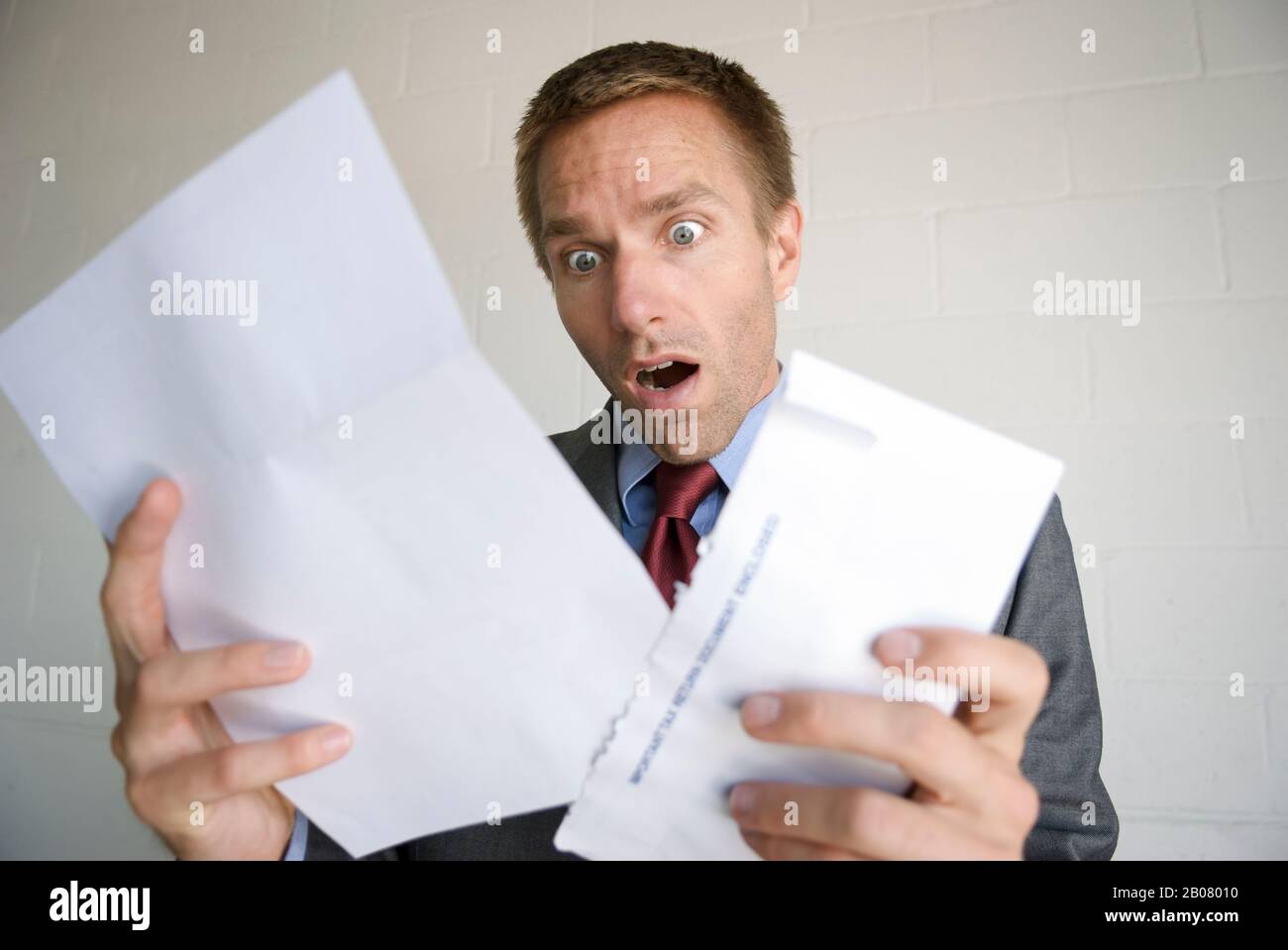 Shocked businessman opening his mail with a wide-eyed gasp of surprise ...