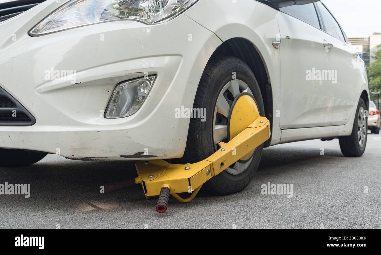 Car wheel blocked by wheel lock because illegal parking violation Stock Photo