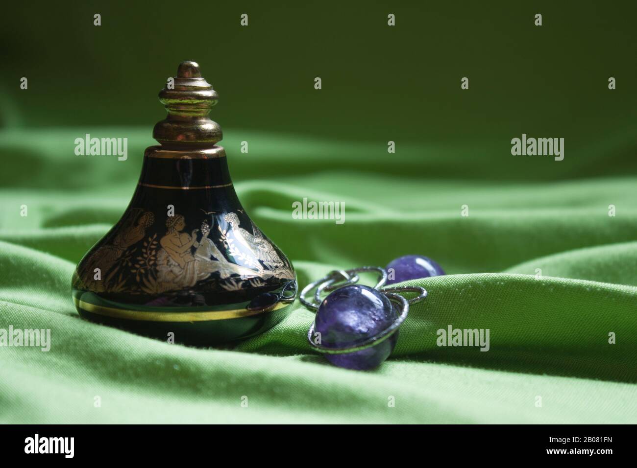 The antique perfume bottle and amethyst on green drapery. Stock Photo
