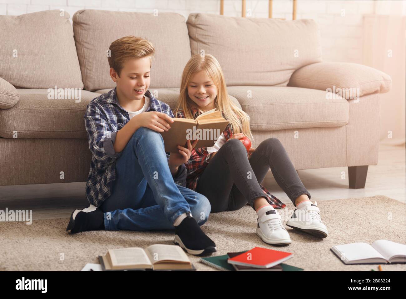 Siblings Reading Book Learning Together Sitting On Floor Indoor Stock Photo