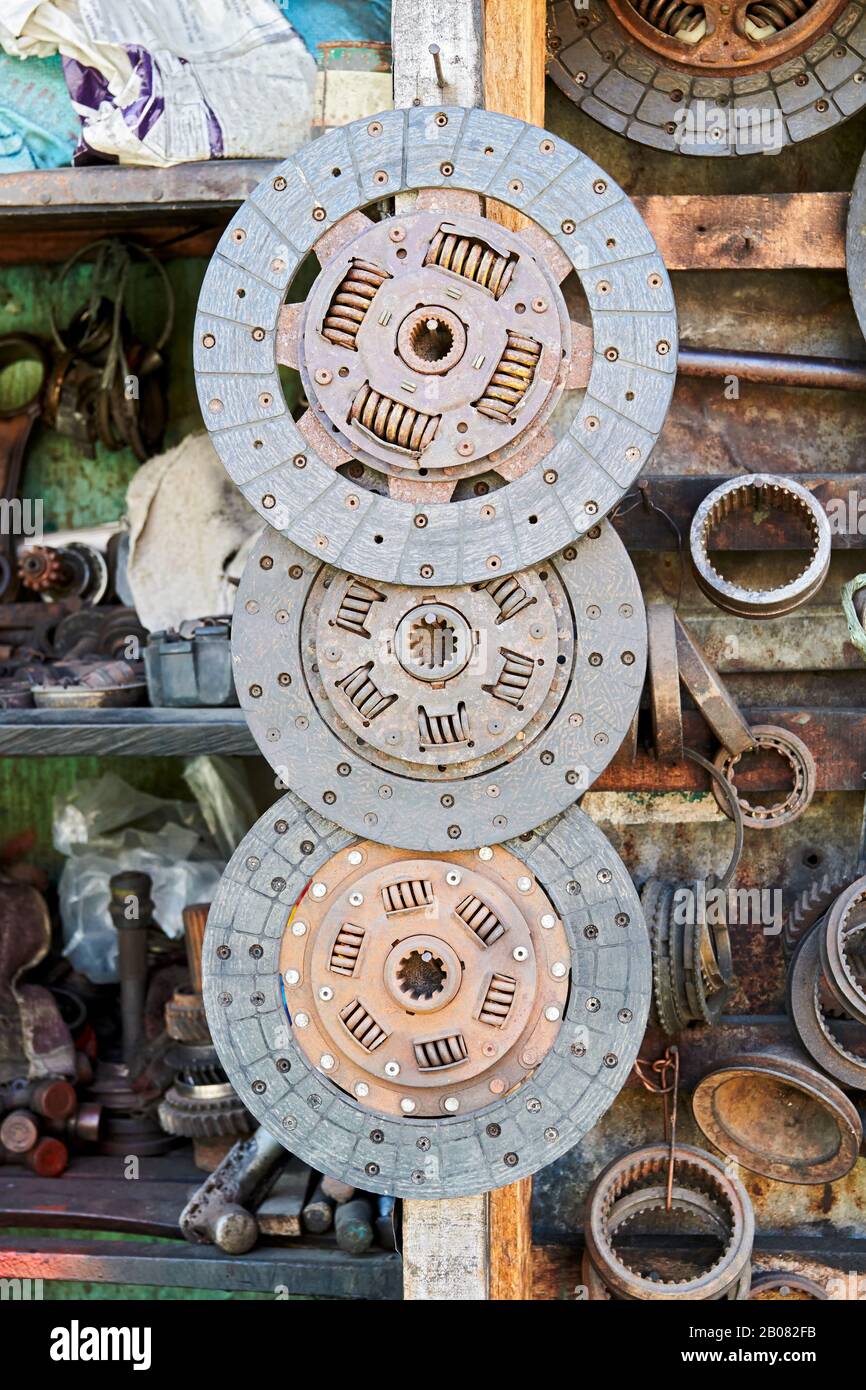 Close-up of an array of old used rusty discs hanging in line in a auto junk shop next to other car parts, seen in Iloilo City, Philippines, Asia Stock Photo