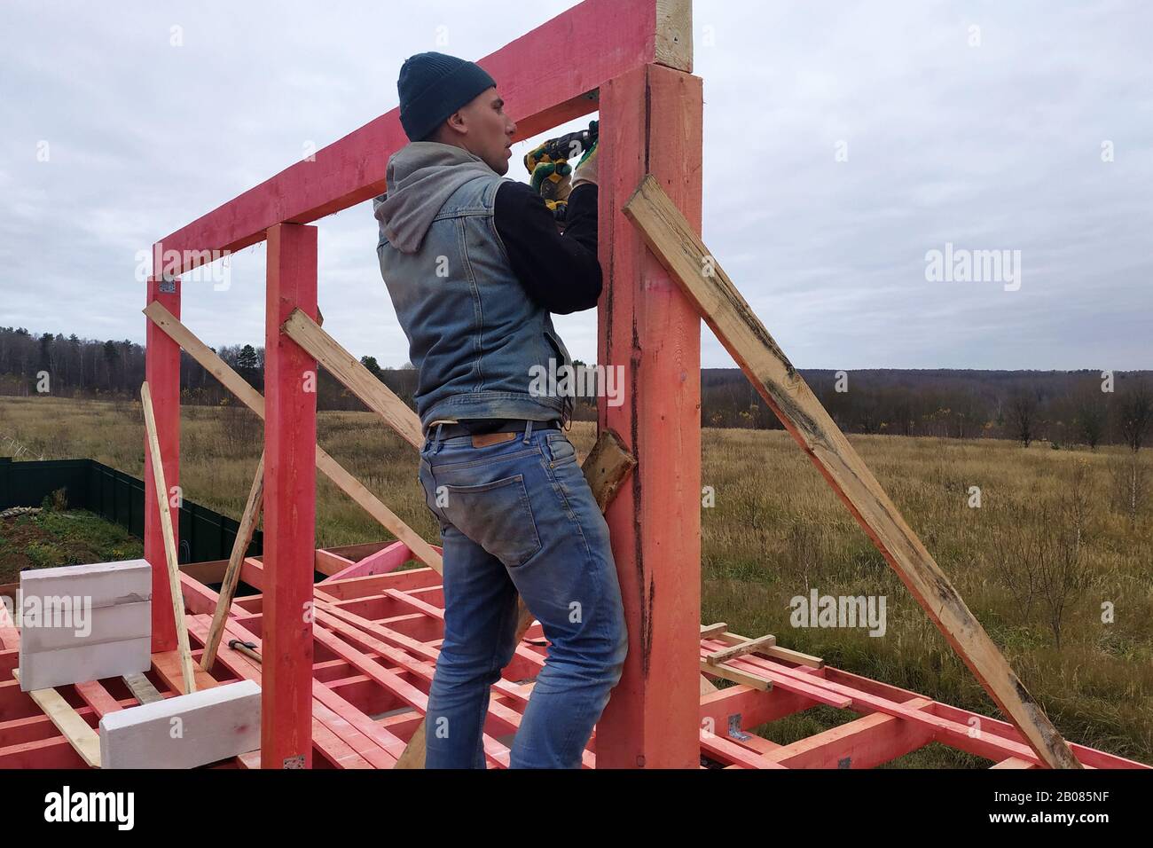 Joiner on roof installation, hammer hammering nail into wooden beam