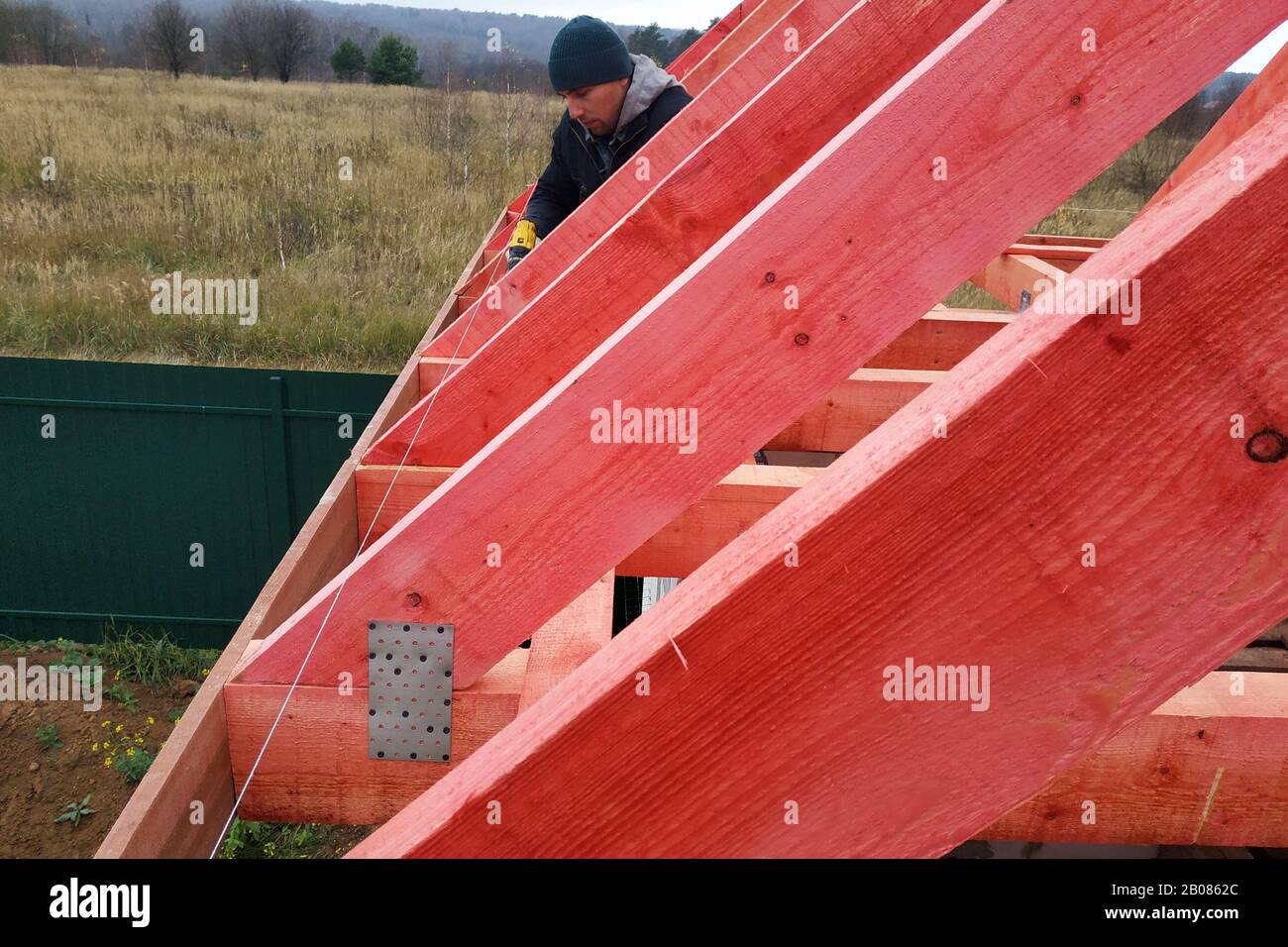 A man fastens two wooden beams with a selftapping screw, installing