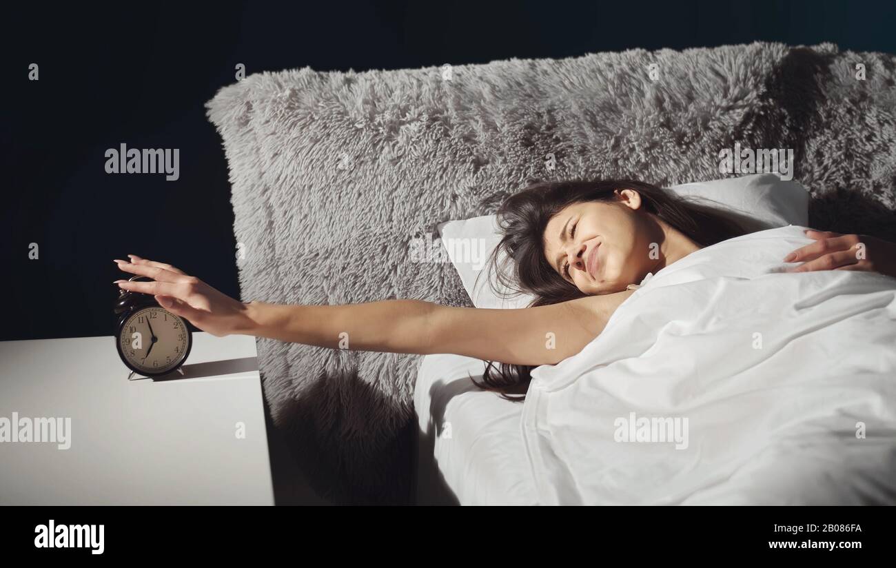 Lady turning off alarm clock Stock Photo Alamy