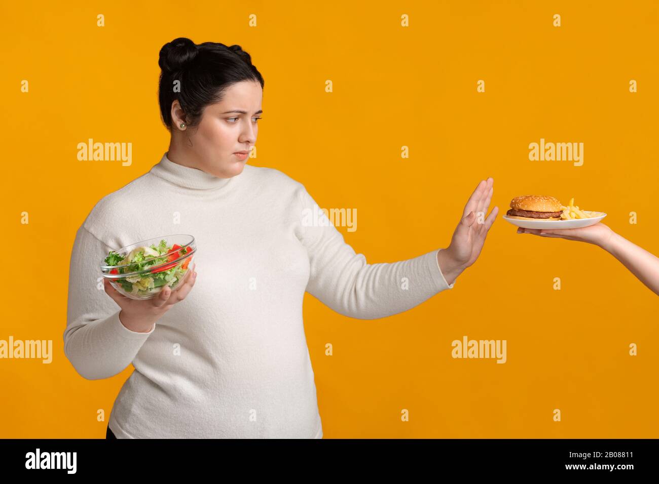 Overweight girl refusing fast food, holding bowl with fresh vegetable ...