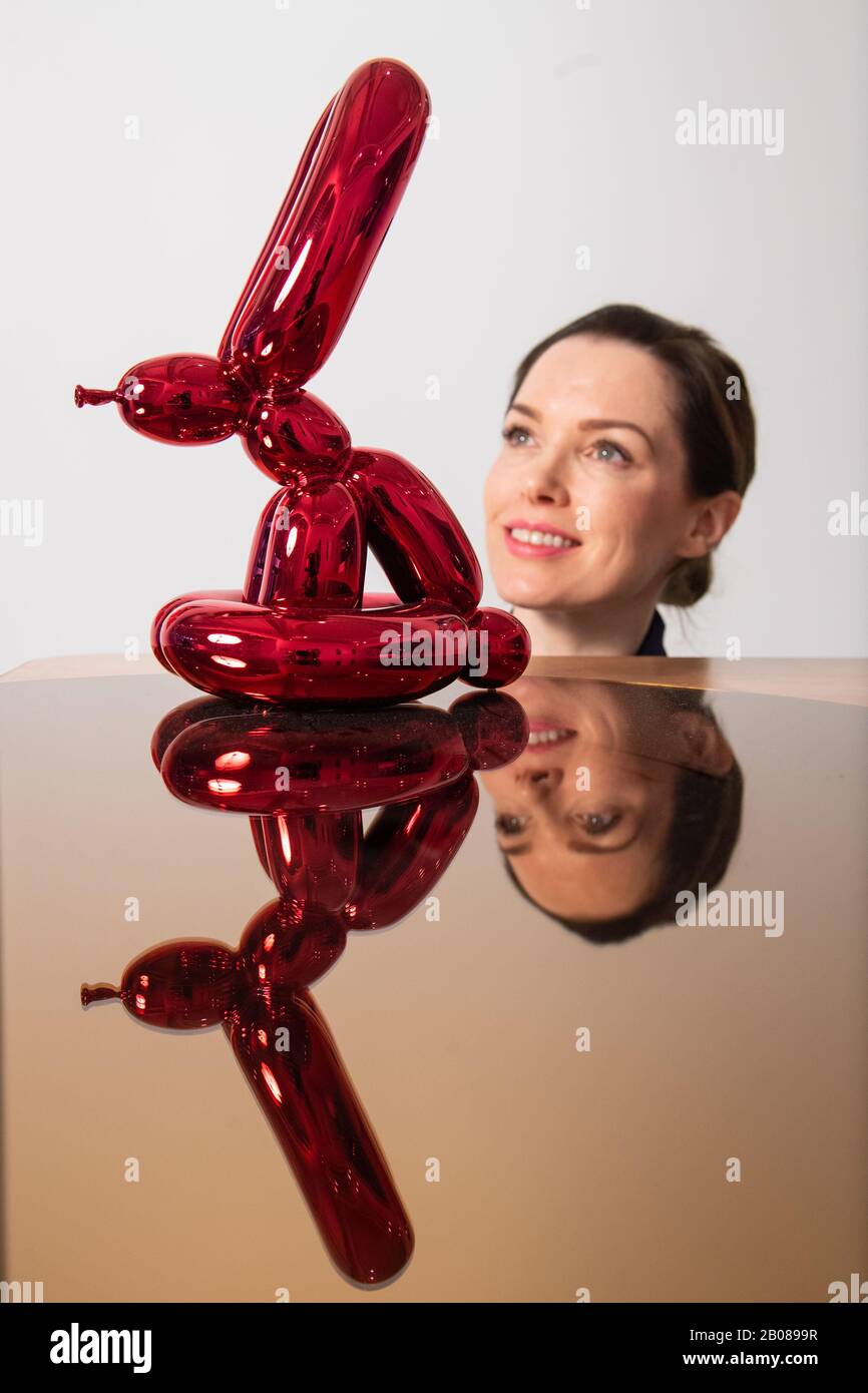 A visitor views 'Balloon Rabbit (red), by Jeff Koons, part of the 'XXI' exhibition display of unseen and rare works by the likes of RETNA, Damien Hirst and Condo, which accompanies the launch of the ARTCELS, a digital platform for blue-chip art investments at The House of Fine Art - HOFA Gallery in London until March 5th. Stock Photo