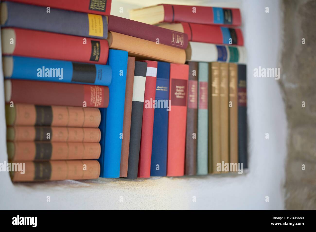 Close up of large set of hardcover books, unorganised Universtiy literature rustic style bookshelf unfocused Stock Photo
