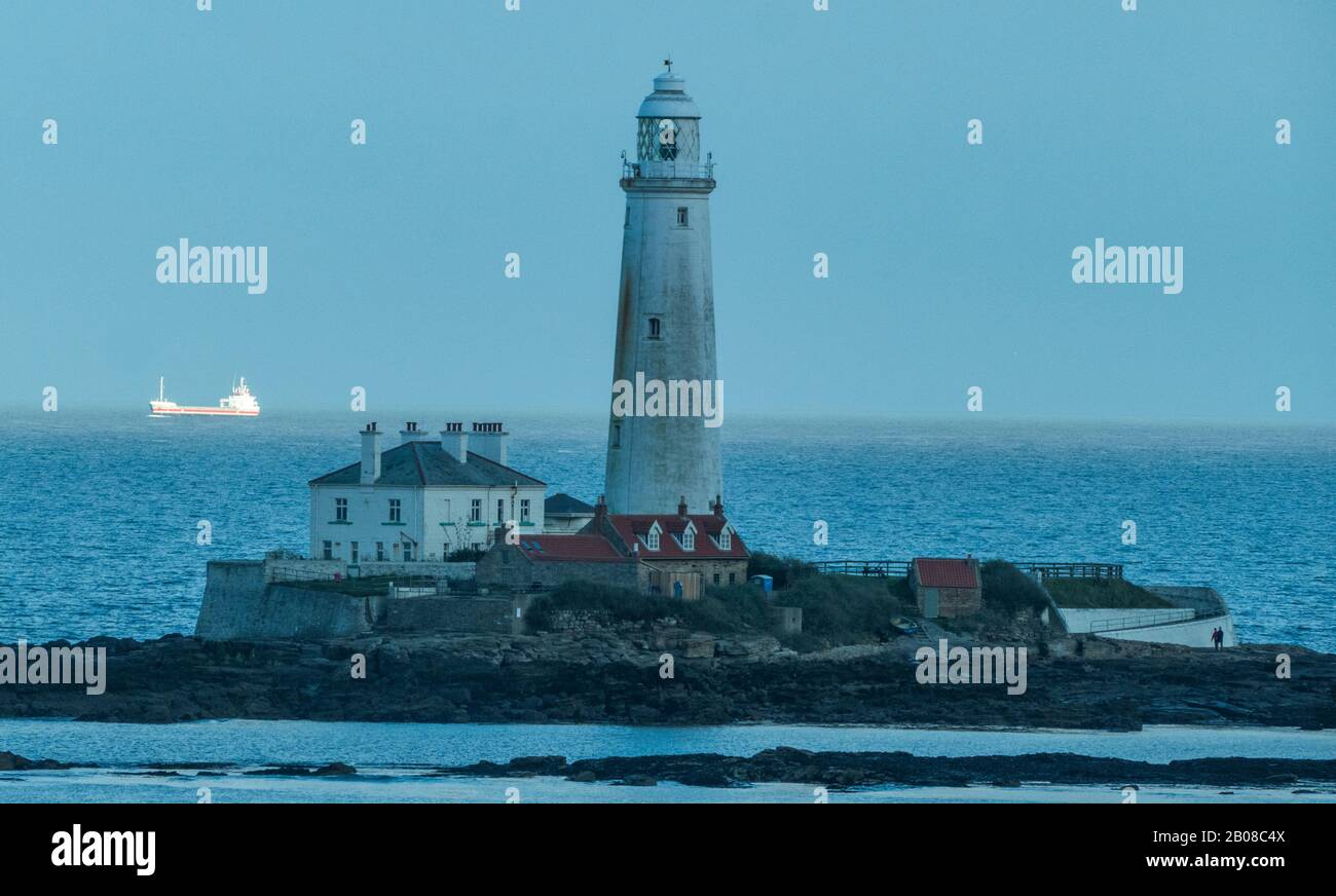 St Mary's lighthouse, with a sunlit passing ship in the background, at Whitley Bay, Tyne and Wear, on the north east coast of England, UK. Stock Photo