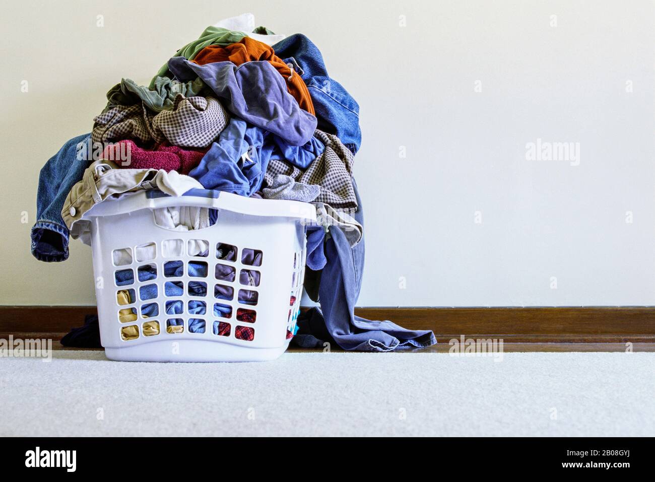 A laundry bin overflowing with dirty clothes. Stock Photo