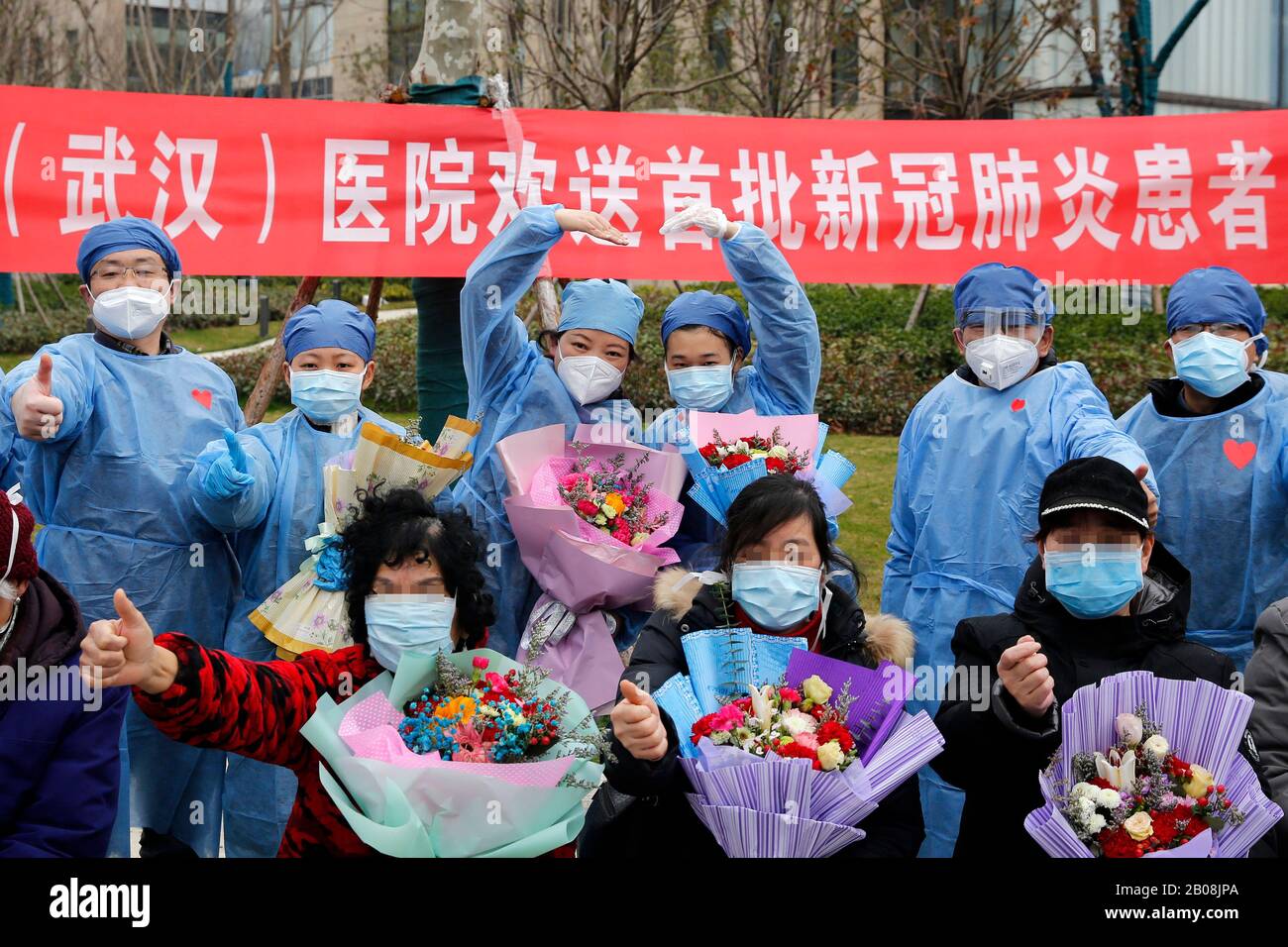 Wuhan, China. 19th Feb 2020. Patients who recovered from novel coronavirus pneumonia (NCP) pose for photos with medical staff in the Taikang Tongji Hospital in Wuhan, central China's Hubei Province, Feb. 19, 2020. A total of 13 patients infected with NCP recovered and were discharged on Wednesday in Taikang Tongji Hospital. (Xinhua/Shen Bohan) Credit: Xinhua/Alamy Live News Stock Photo