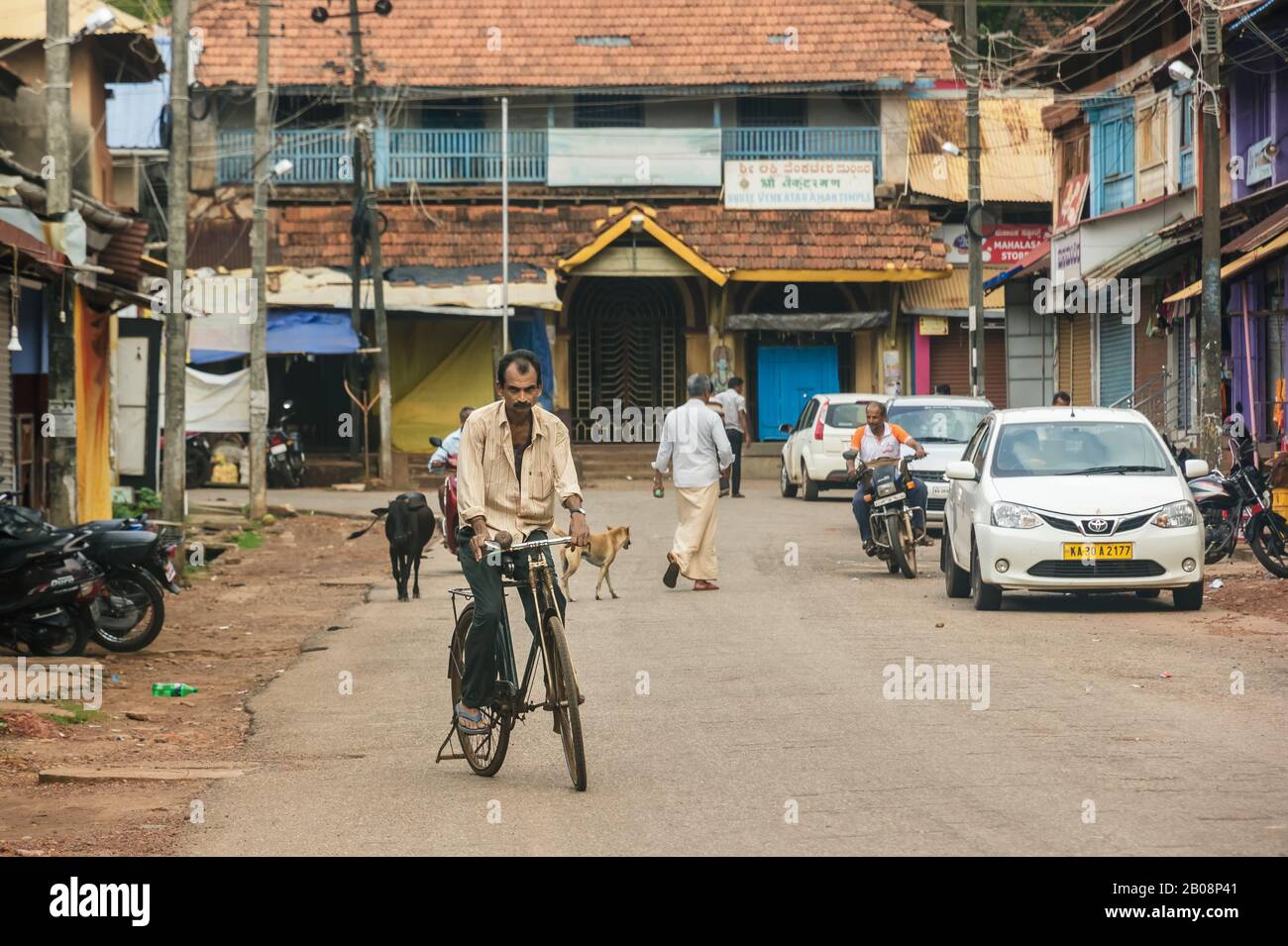 Candid street portrait of a man rides a bicycle on a quiet street in the village of Gokarna. Stock Photo