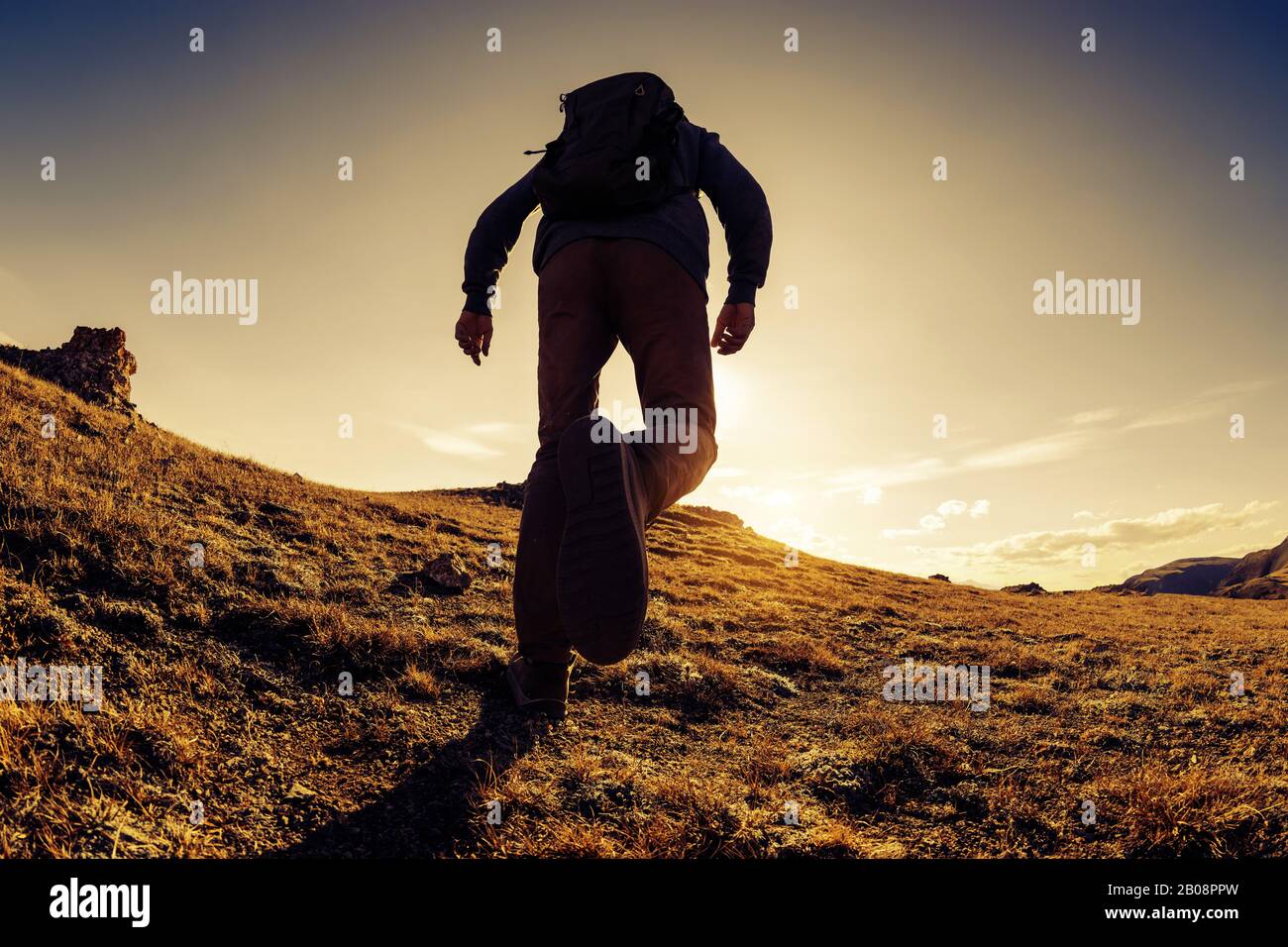 Unrecognized traveler or hiker walks in mountains area at sunset time Stock Photo
