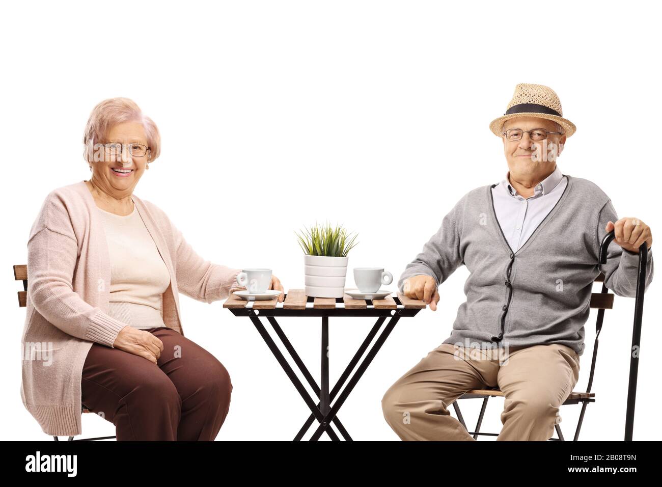 Seniors sitting at a table with a cup of coffee and smiling at the