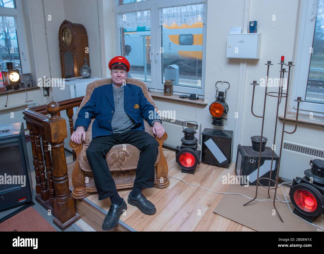 06 February 2020, Mecklenburg-Western Pomerania, Sülstorf: The Berlin taxi driver Michael Böhmke is sitting in his living room at the Sülstorf train station wearing a railway cap. A good two years ago he bought the station building on the railway line from Ludwigslust to Schwerin at an auction on Ebay. Gradually, he now wants to extend and renovate the building; he has already collected numerous collector's items relating to railway history. Photo: Jens Büttner/dpa-Zentralbild/ZB Stock Photo