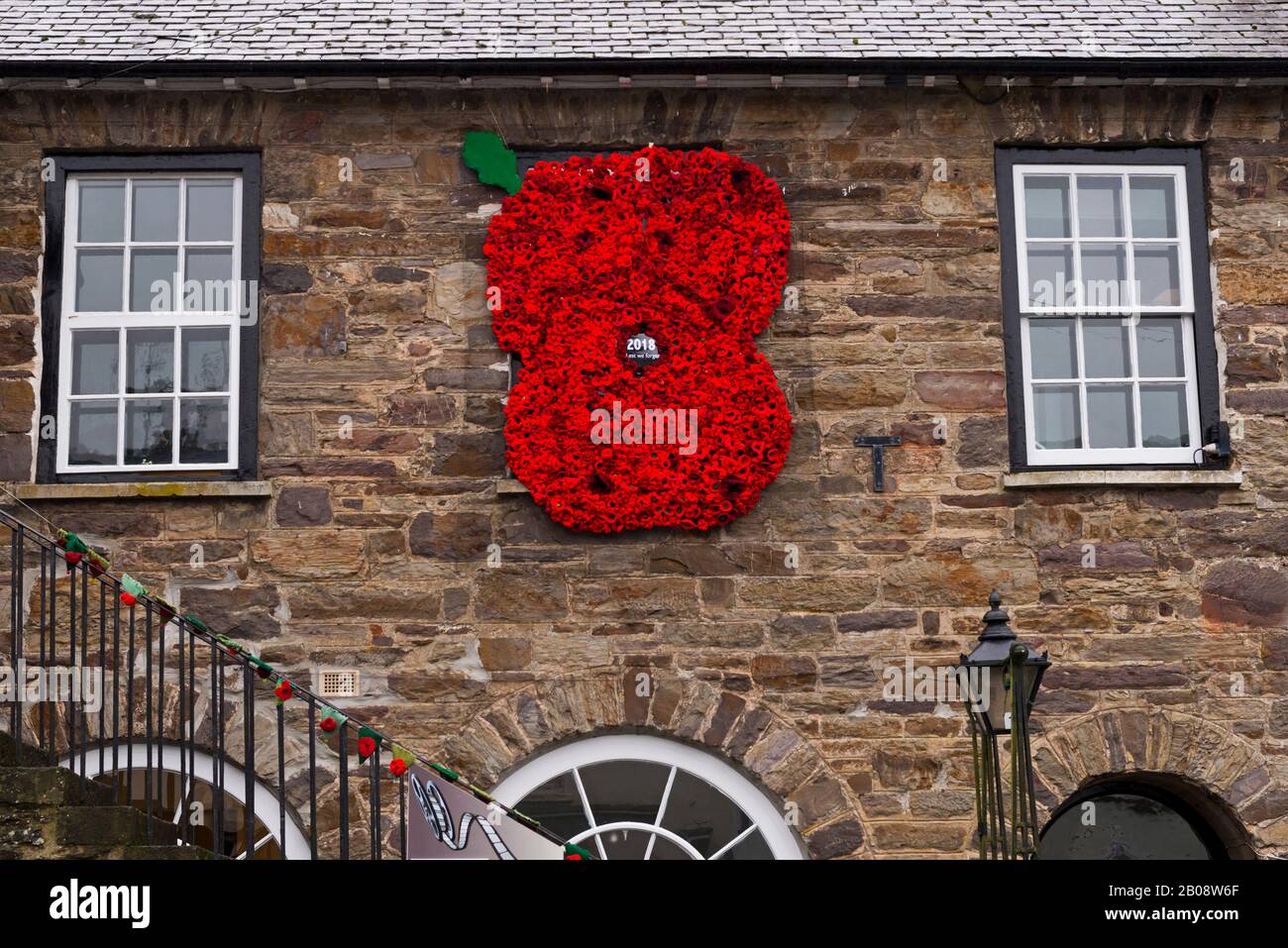 large knitted Poppy on the wall of the Village Hall in Dulverton, Somerset, Enlgand, part of the Exmoor National Park. Stock Photo