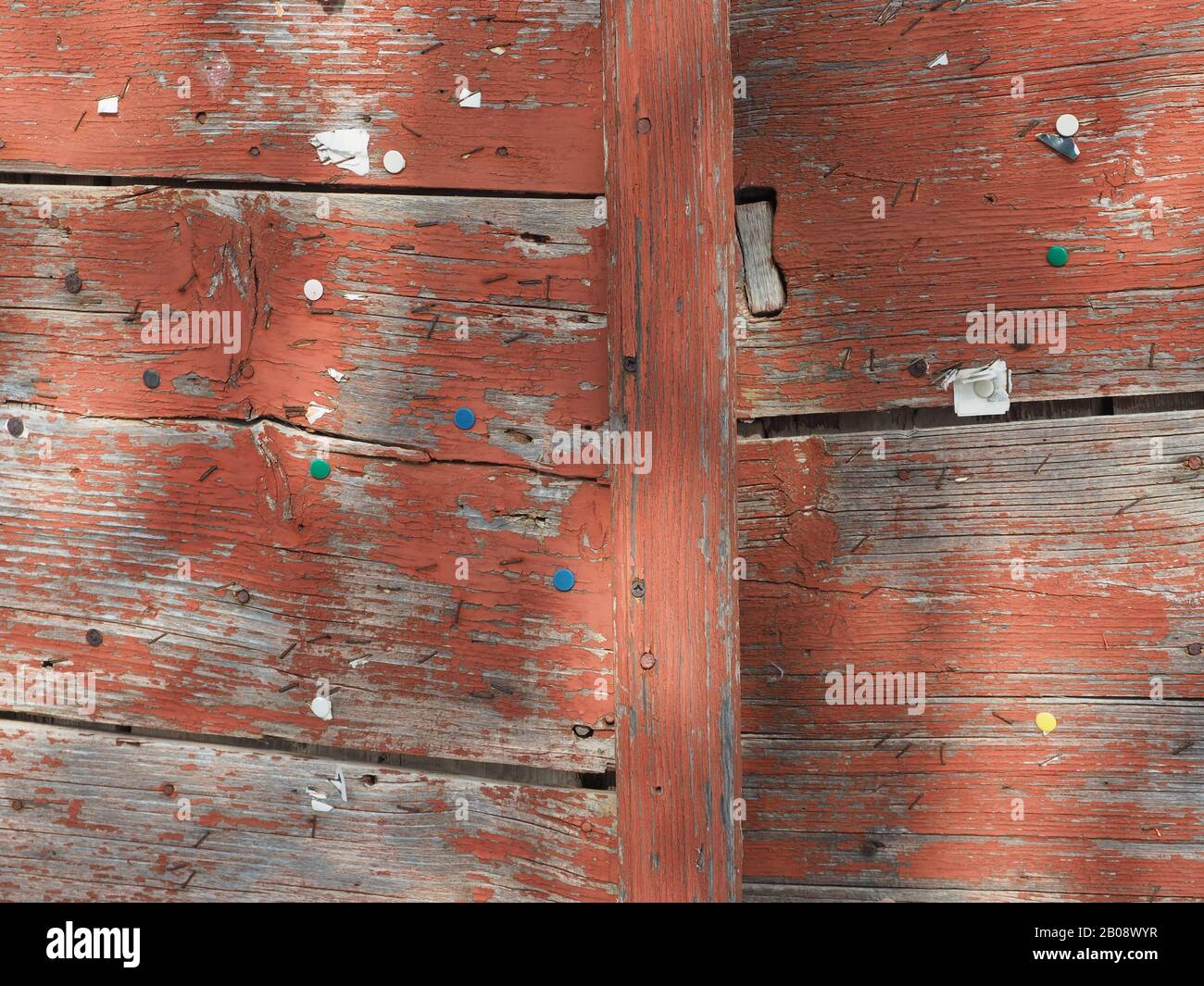 Worn, old wooden door studded with multi-coloured drawing pins in Kythira, Greece Stock Photo