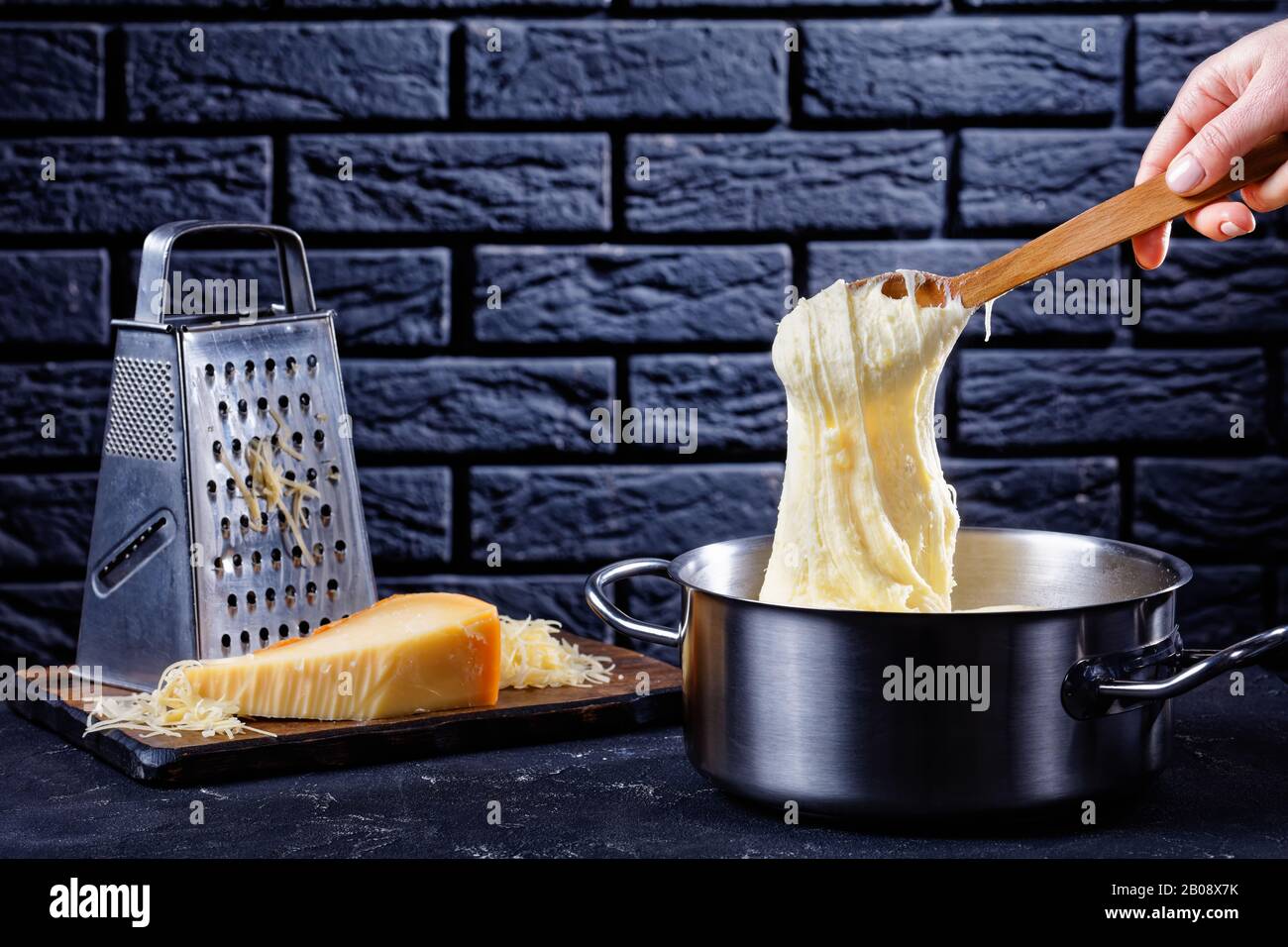 Aligot Comforting Cheese Enhanced Mashed Potato Dish In A Pot With A Brick Wall At The Background Woman Hand Pulls Spoon Away From The Pot And It M Stock Photo Alamy