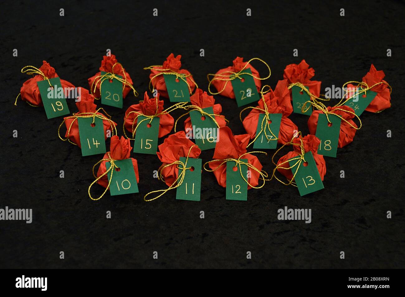 Twenty four little presents wrapped in red, green tags golden numbers from 1 to 24 on black as self made advent calendar - 10th of December Stock Photo
