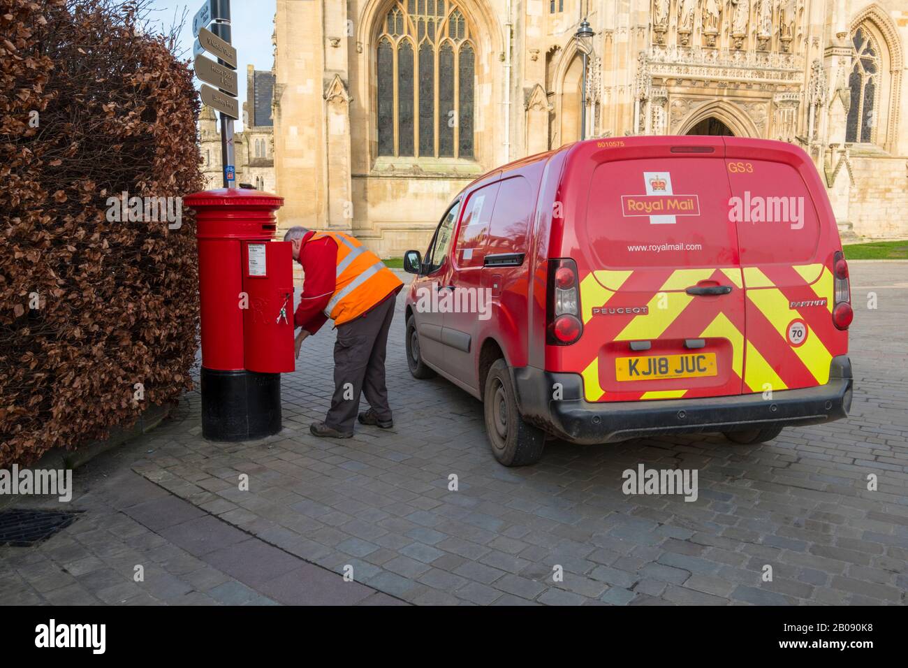 A Postman empties a post box outside Gloucester Cathedral. Stock Photo