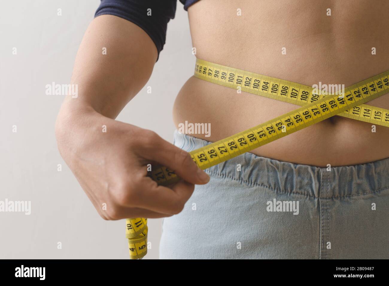 A young woman measures her waist with a measuring tape. The concept of losing weight. Stock Photo