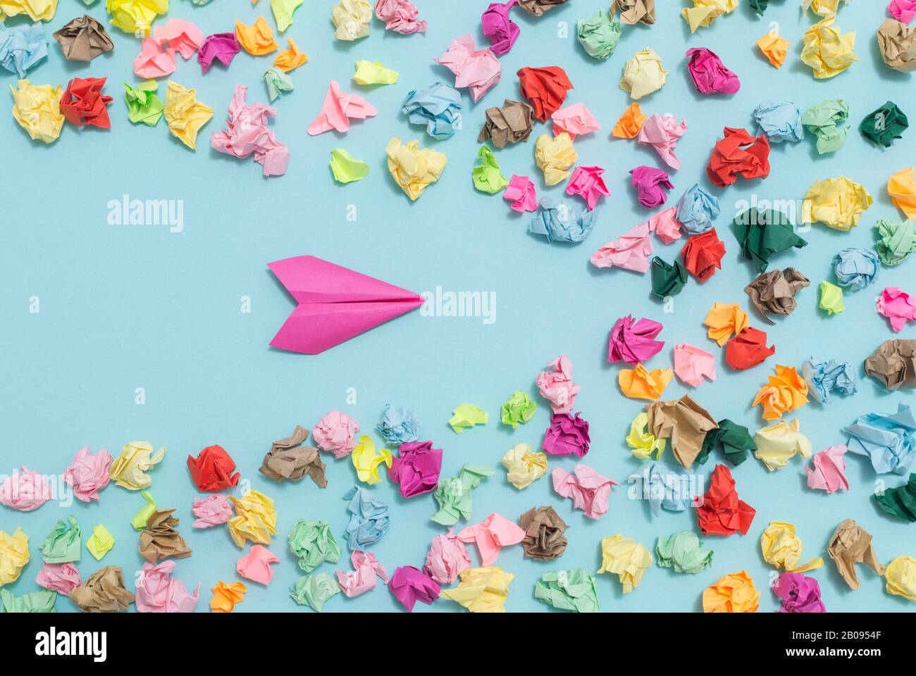 Leadership concept. Creative idea of doing business. A paper plane flies away from crumpled multi-colored papers. Stock Photo