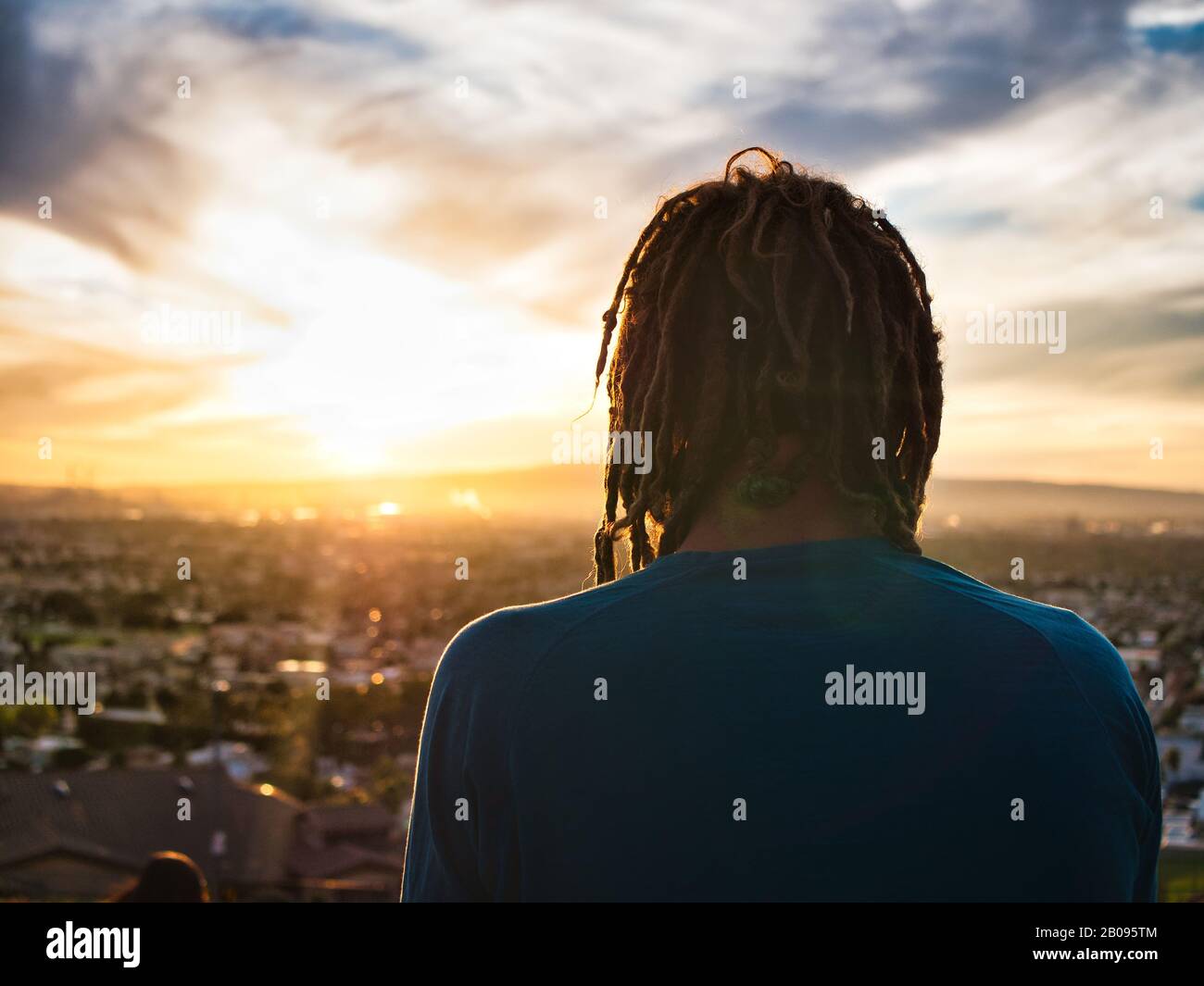 Unrecognizable man with dreadlocks admiring nature during sunset Stock Photo