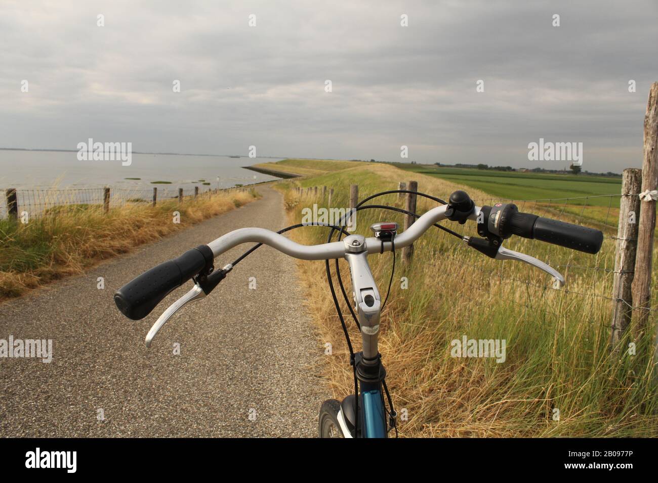 a bike handlebar on rop of a dike crossing in the seawall along the westerschelde sea at the dutch coast in zeeland in summer with high tide Stock Photo