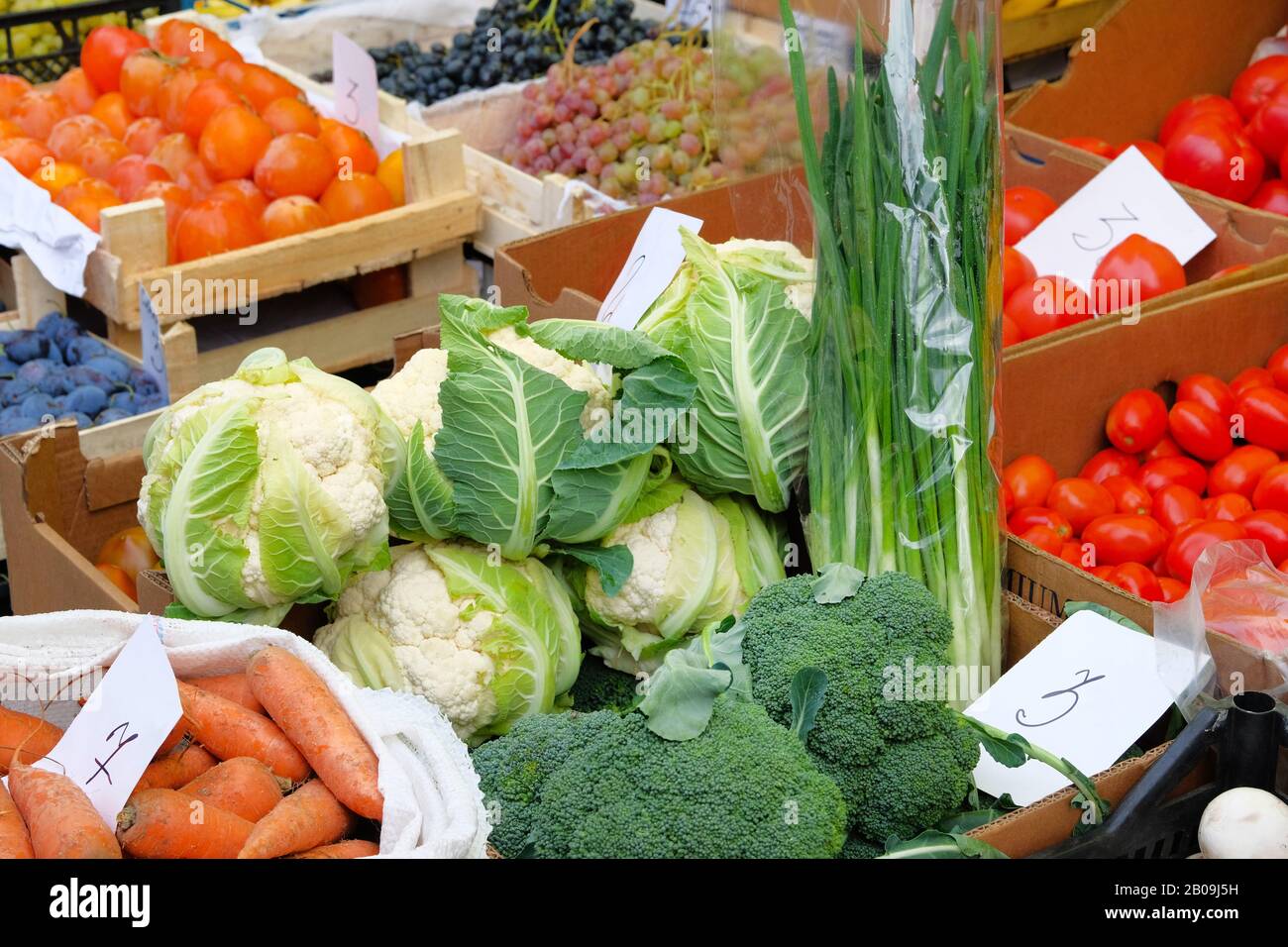 Vegetables are sold in mediterranean farmers fair. Healthy local food market. Broccoli, cauliflower, tomatoes, green onions, carrots, persimmon, grape Stock Photo