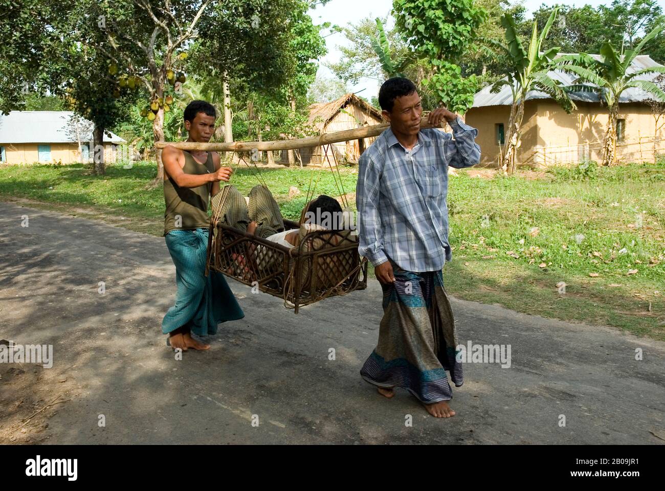 Men from the Chakma community carry a patient on a traditional cane basket to the doctor. Matiranga, Khagrachari, Bangladesh. May 11, 2010. Stock Photo
