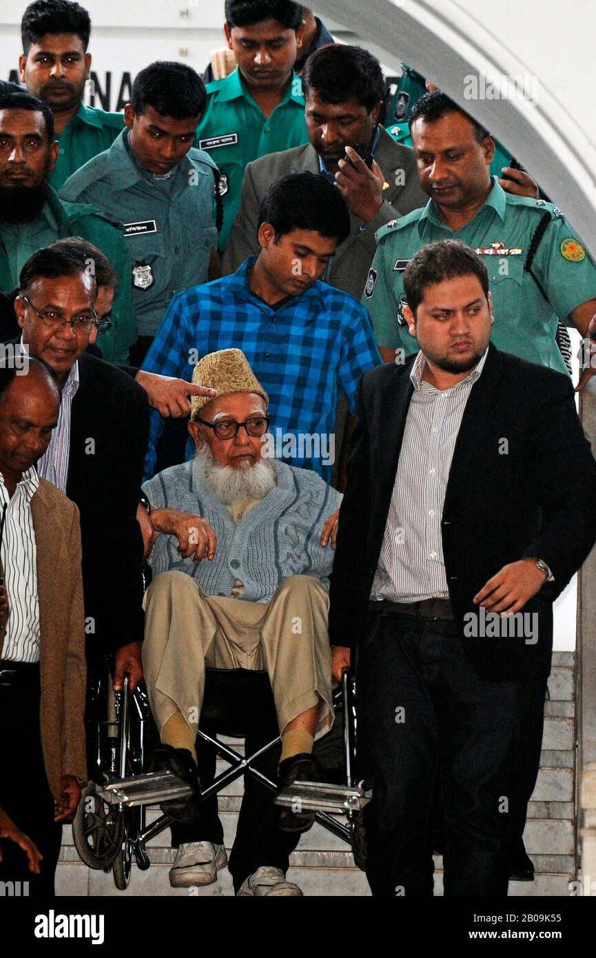 Police escort former Jamaat-e-Islami chief Ghulam Azam, in a wheelchair, as he exits the Bangladesh International Crimes Tribunal. His bail plea was rejected by a special tribunal that sentenced him with imprisonment pending trial on charges committed against humanity during the liberation war of 1971. Dhaka, Bangladesh. January 11, 2012. Stock Photo