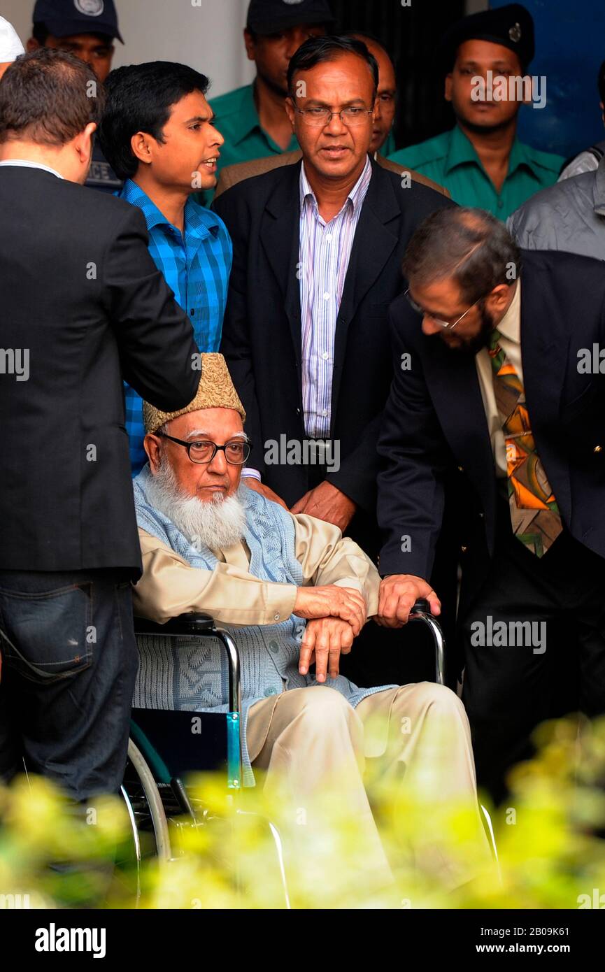 Police escort former Jamaat-e-Islami chief Ghulam Azam, in a wheelchair, as he exits the Bangladesh International Crimes Tribunal. His bail plea was rejected by a special tribunal that sentenced him with imprisonment pending trial on charges committed against humanity during the liberation war of 1971. Dhaka, Bangladesh. January 11, 2012. Stock Photo