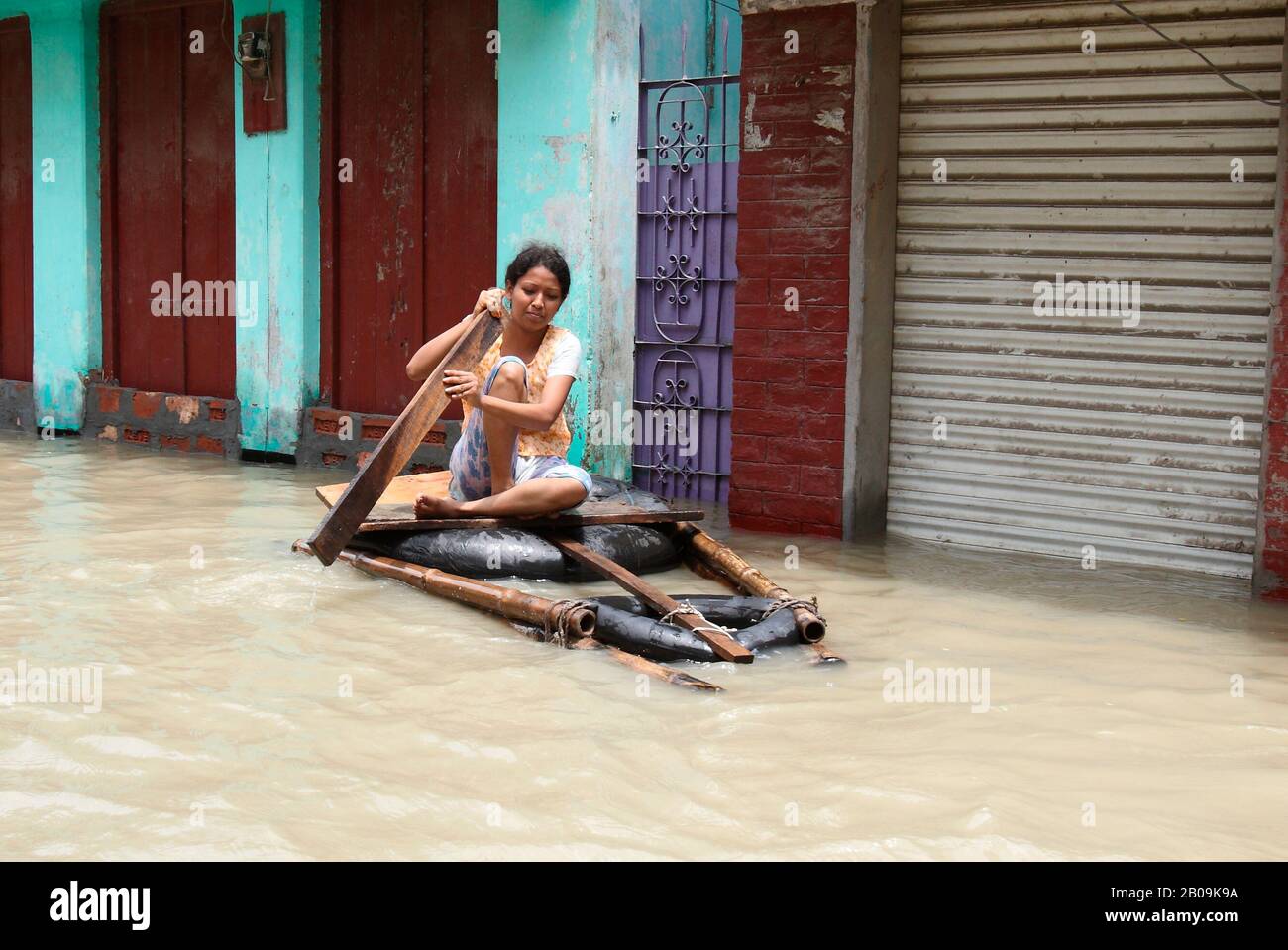 A woman paddles a makeshift raft through a flooded neighbourhood in Sirajganj. Nearly 0.7 million people of the northern district have been affected by the severe flood of 2007. Sirajganj, Bangladesh. July 31, 2007. Stock Photo