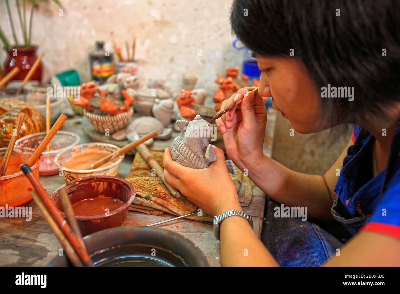 A woman paints a ceramic toy at her workshop in the Ceramic Village, Guangzhou Province, China. September 19, 2009. Stock Photo
