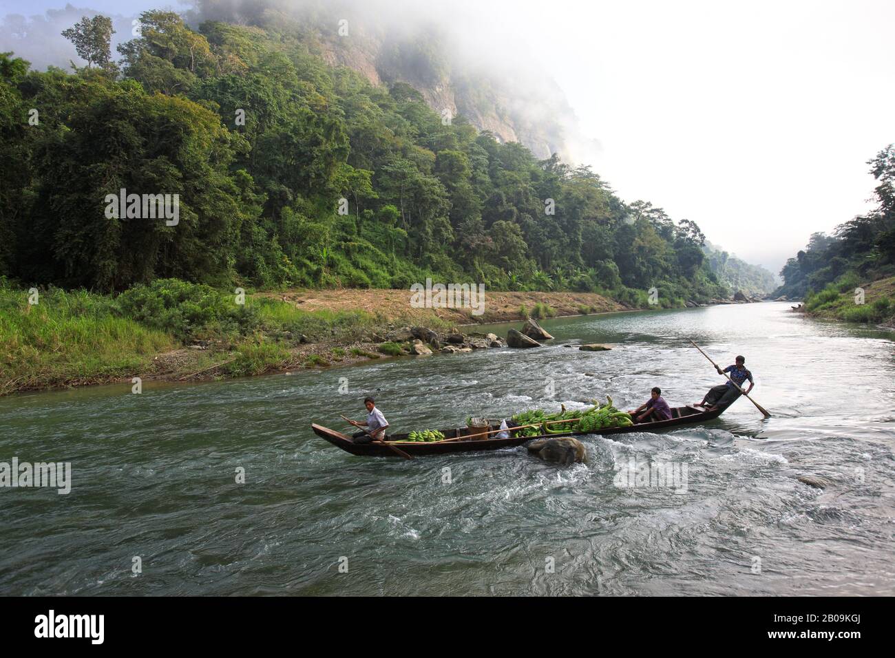 Ethnic men row a boat against the strong current of the Sangu river, in Tindu, Bandarban, Bangladesh. November 2010. Stock Photo