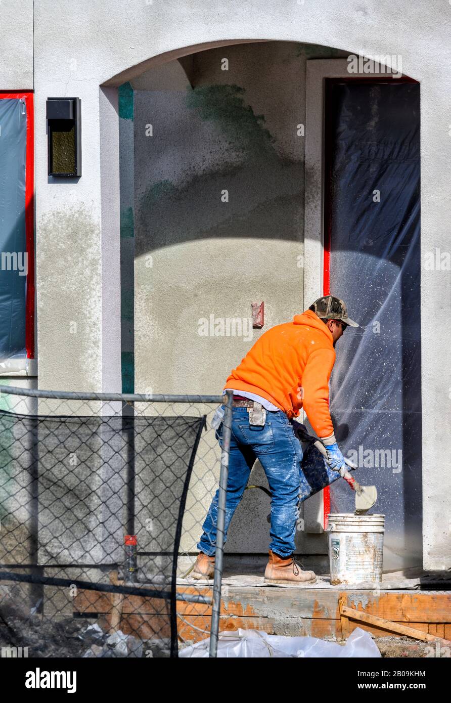 Construction worker putting decorative plaster on house exterior Stock Photo