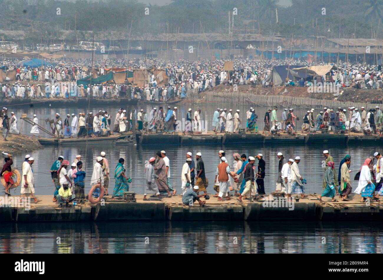 Devotees walk across makeshift bridges to participate in the annual Bishwa Ijtema on the bank of the Turag river in Tongi. Bishwa Ijtema is the largest Muslim Pilgrimage after Haj, in which several million Muslims from around the world take part. Tongi, Dhaka, Bangladesh. January 31, 2009. Stock Photo
