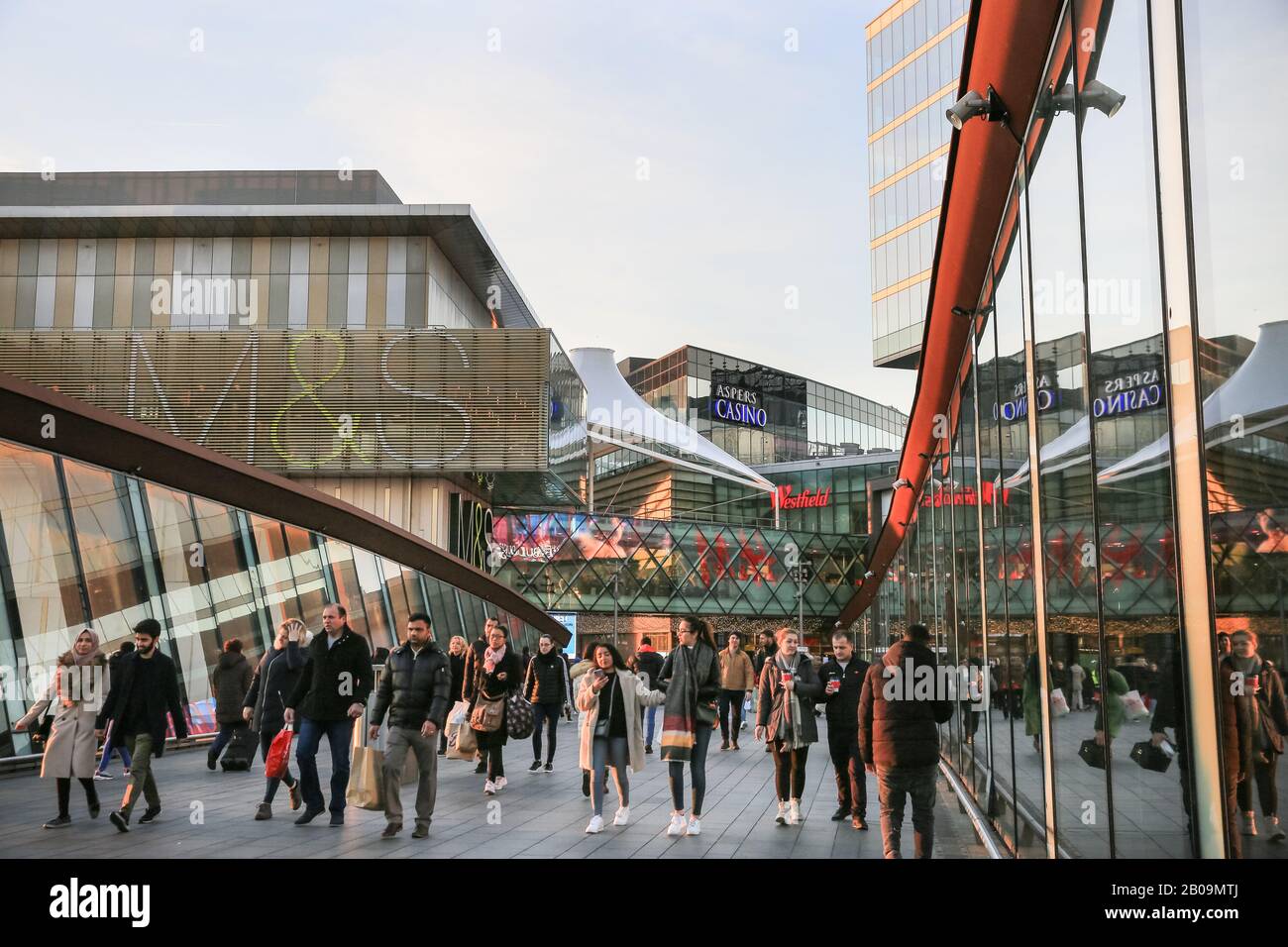 People and shoppers walking towards Westfield Shopping Centre, exterior with brand logos and signs, Stratford, London, UK Stock Photo