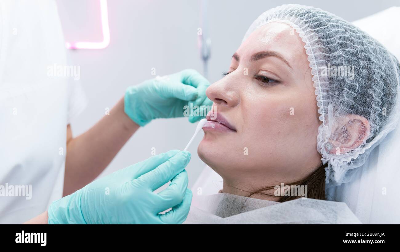 The young beautician doctor preparing to making injection in female lips. The doctor cosmetologist makes lip augmentation procedure. Concept of beauty Stock Photo