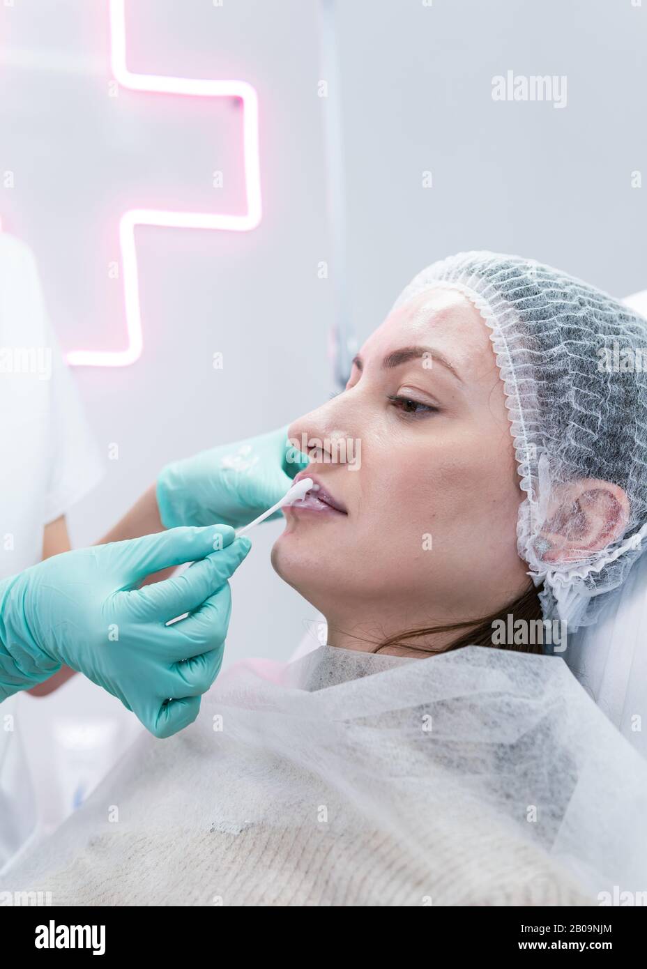 The young beautician doctor preparing to making injection in female lips. The doctor cosmetologist makes lip augmentation procedure. Concept of beauty Stock Photo