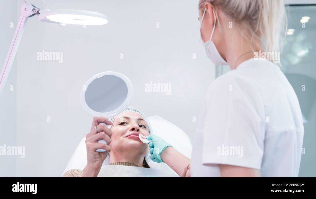 The young beautician doctor preparing to making injection in female lips. The doctor cosmetologist makes lip augmentation procedure. Concept of beauty Stock Photo