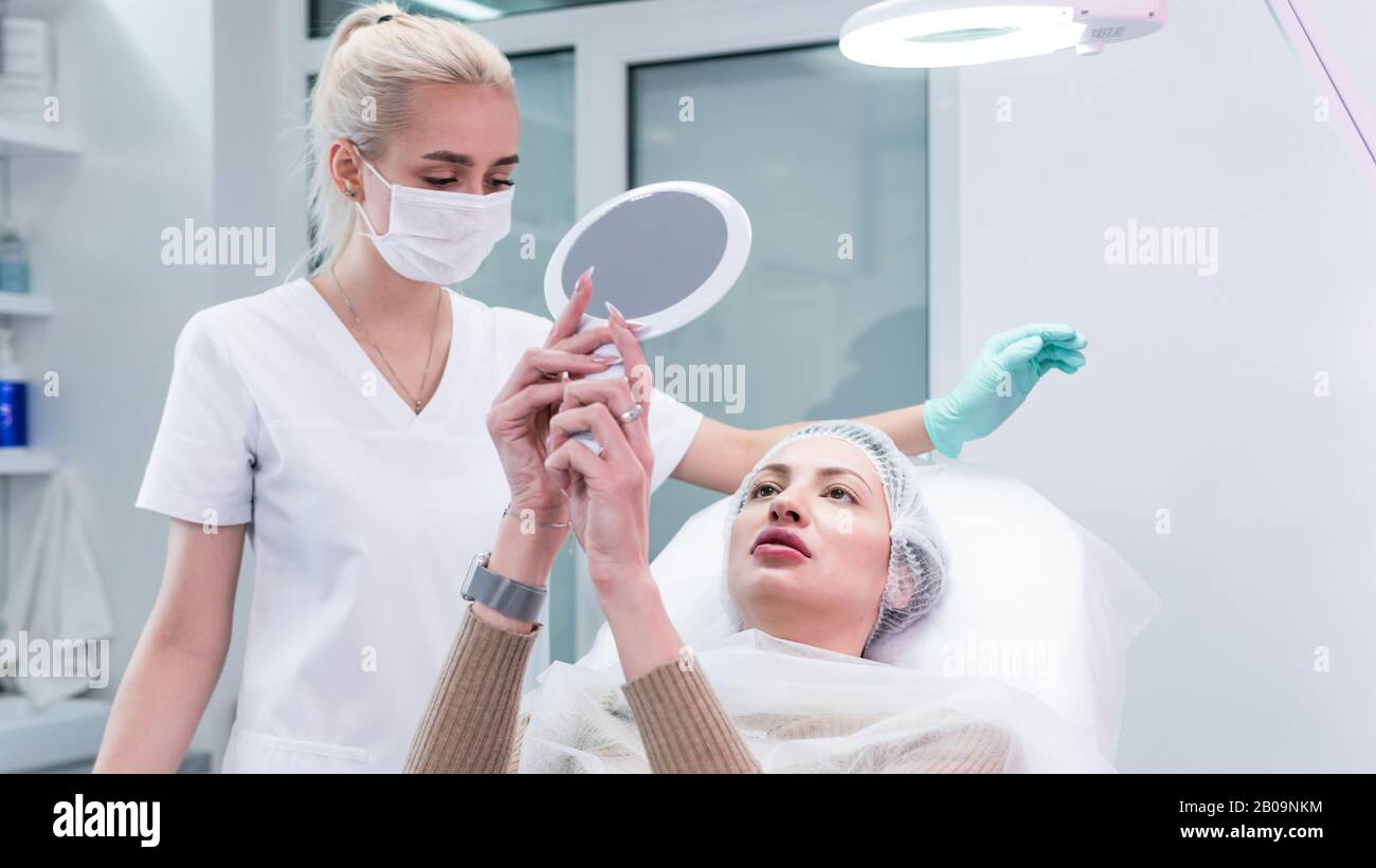 The young beautician doctor preparing to making injection in female lips. The doctor cosmetologist makes lip augmentation procedure. Concept of beauty Stock Photo